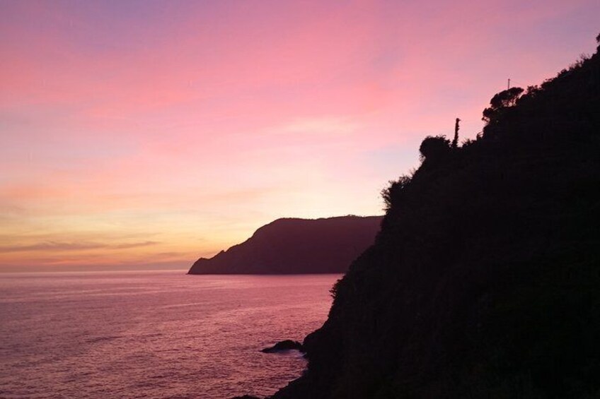 Paesaggio costiero con una scogliera e una distesa d'acqua al tramonto. 2