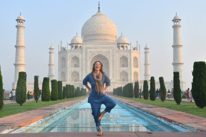 Eine Person steht vor dem Taj Mahal, wobei dessen vier Minarette und die zentrale Kuppel sichtbar sind. 3