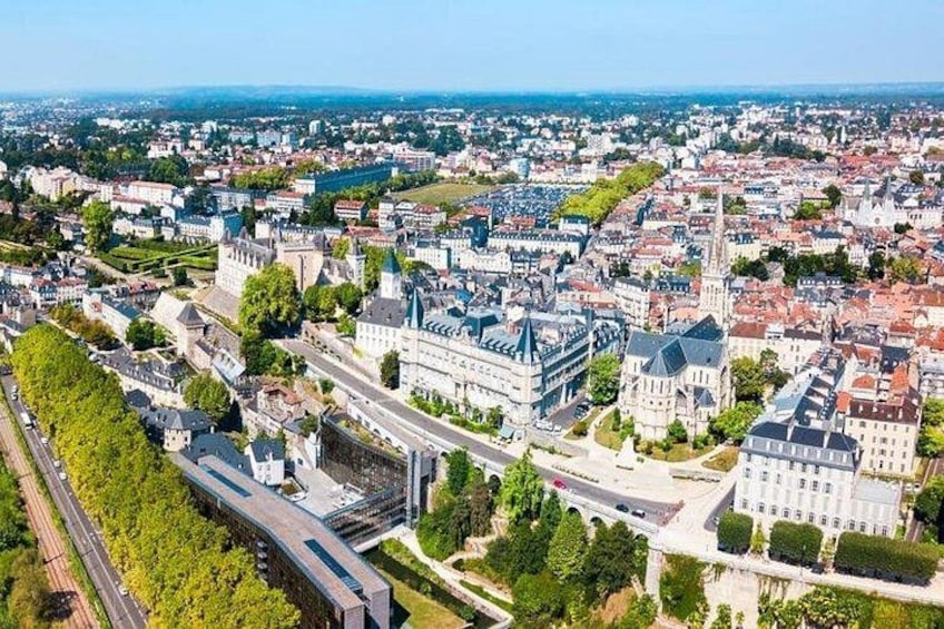 Une vue aérienne d’une ville avec un bâtiment imposant qui ressemble à un château, une ligne de chemin de fer et une zone urbaine densément construite. 1