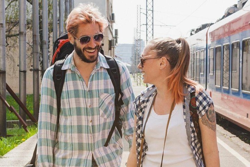 Deux personnes se tiennent près d’une voie ferrée, avec un train en arrière-plan. 2