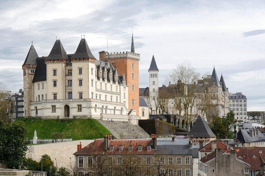 Un château historique doté de nombreuses tours, entouré de bâtiments urbains et bordé d’une zone verdoyante. 4