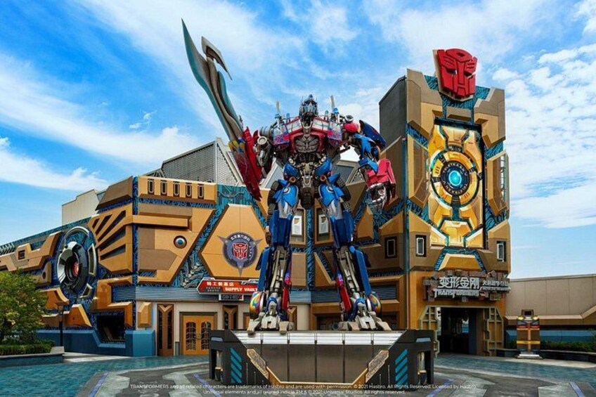 A large Transformers statue in front of a building with a blue sky. 3