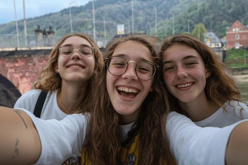 Three people taking a selfie with a bridge and greenery in the background. 2