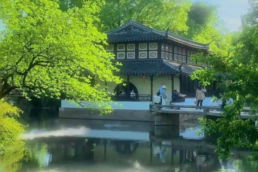 A traditional building with a tiled roof, surrounded by lush greenery and a calm water body reflecting the structure. 3