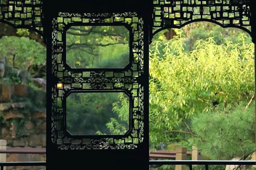 A traditional Chinese gate with intricate lattice work and two rectangular windows. 2