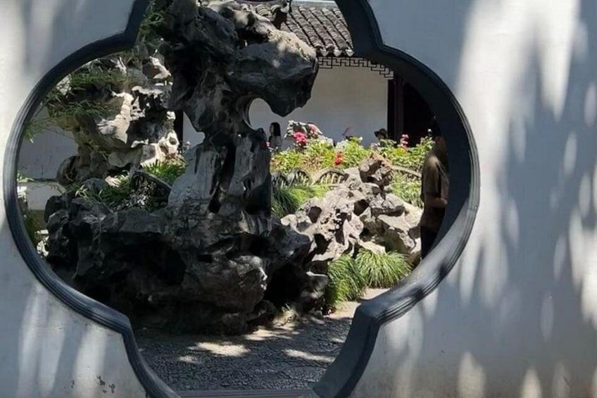 A rock garden with a large rock formation, a small pond, and a pathway. 5