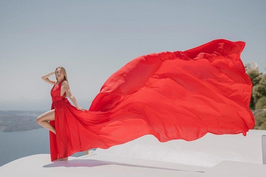 Una persona con un vestido rojo está de pie sobre una estructura blanca, con un tejido rojo ondeando a su alrededor. 4