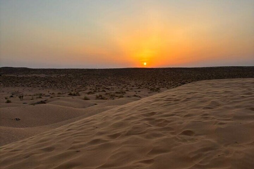 A desert landscape with sand dunes and a sunset. 1