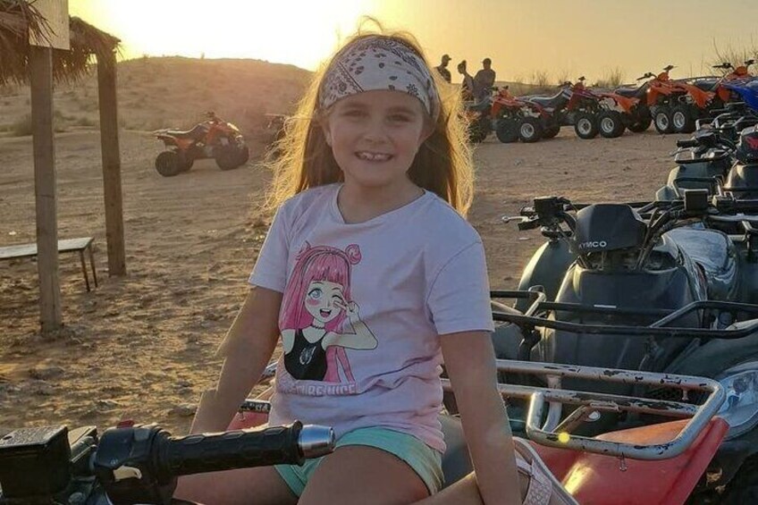 A person sitting on a red ATV in a sandy area with multiple ATVs in the background. 3