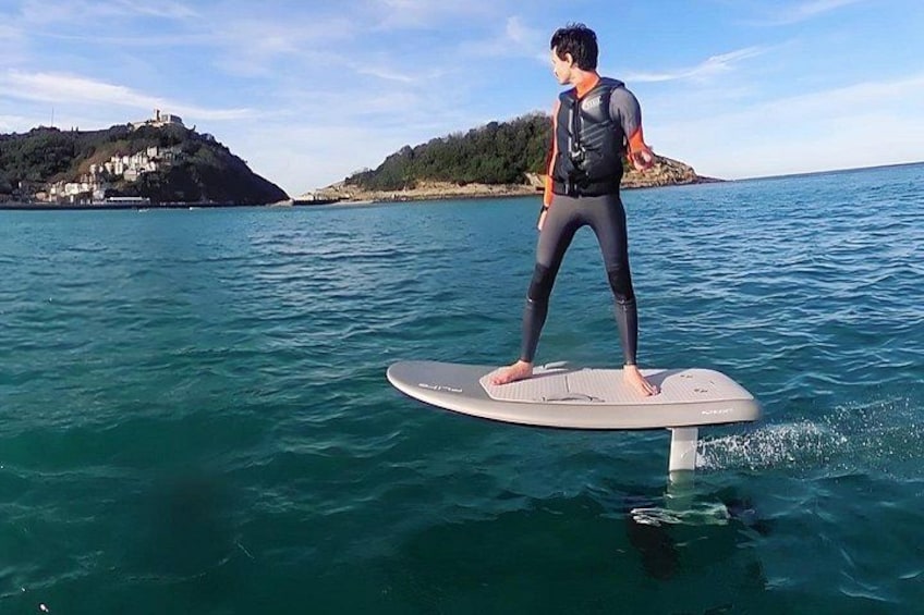 Une personne fait du stand-up paddle sur une mer calme, avec une ville côtière en arrière-plan. 5