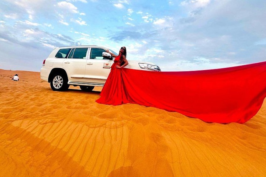 A white SUV in a desert with a red fabric draped over it. 3