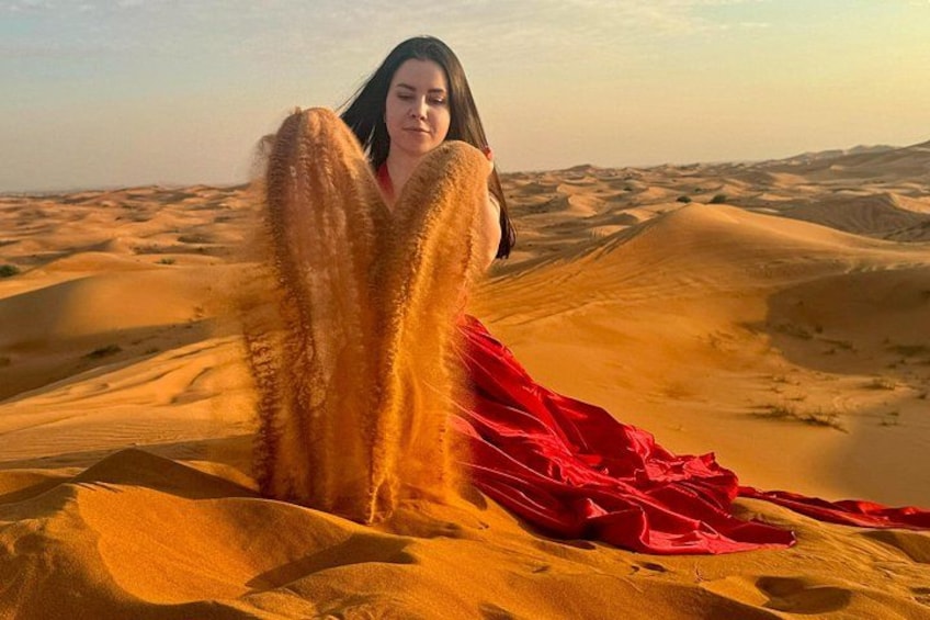 A person in a red dress sitting on sand dunes in a desert landscape. 5
