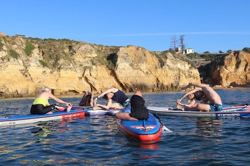 People on paddleboards in calm water with cliffs in the background. 2