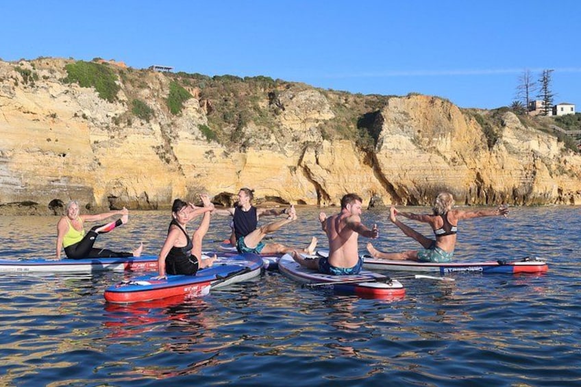 People on paddleboards in a body of water with cliffs in the background. 3