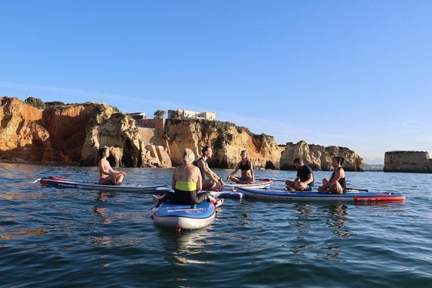 People sitting on kayaks in calm water with cliffs in the background. 4