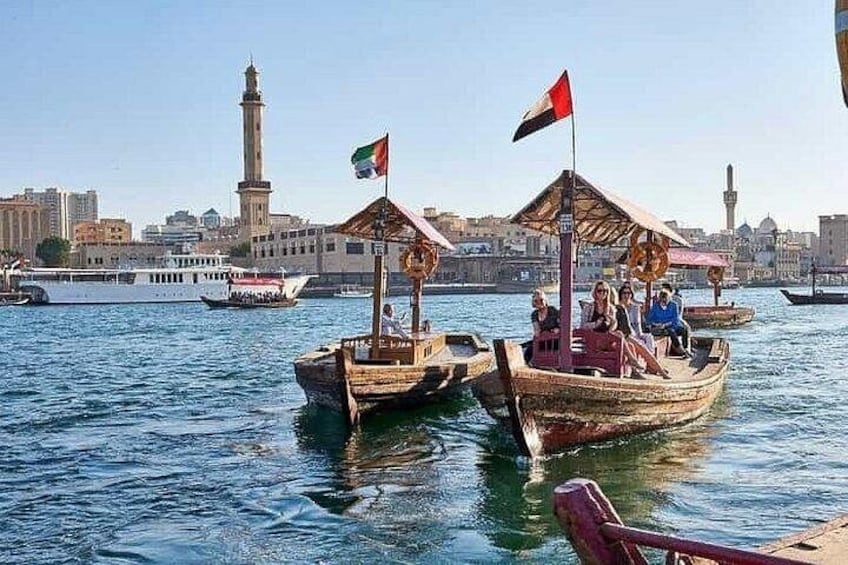 Botes de madera tradicionales con banderas, una mezquita y un minarete al fondo. 3