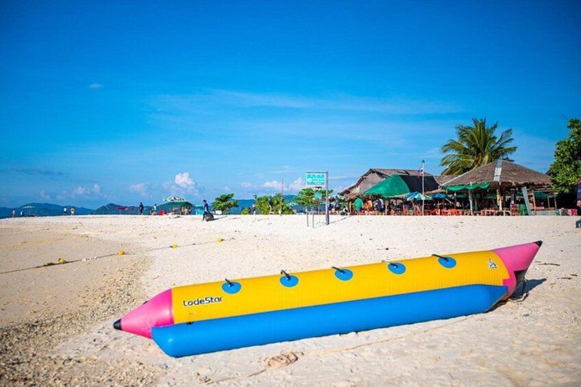 A beach with a colorful inflatable tube, palm trees, and a clear sky. 3