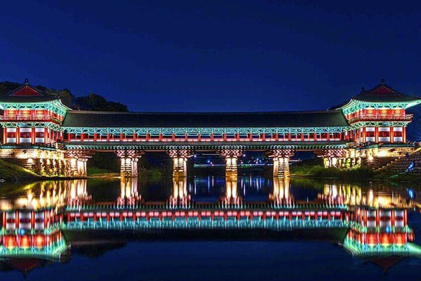 A traditional building with a reflection in the water, illuminated by lights. 2