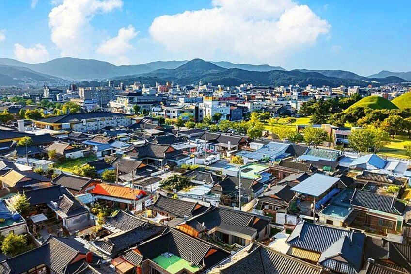 A densely packed urban area with traditional and modern buildings, surrounded by mountains. 3