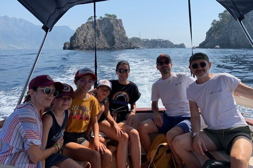 A group of people on a boat with rocky islands in the background. 1