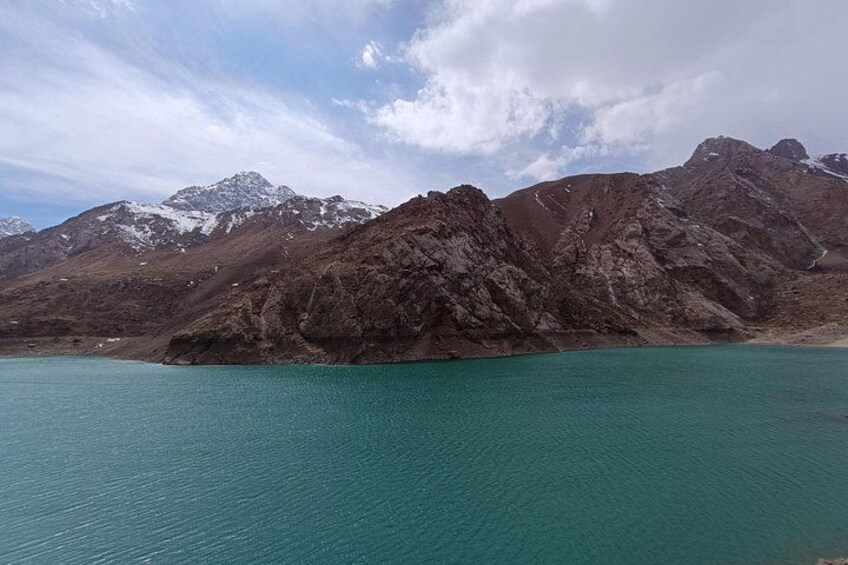 A mountain range with a turquoise lake in the foreground. 1