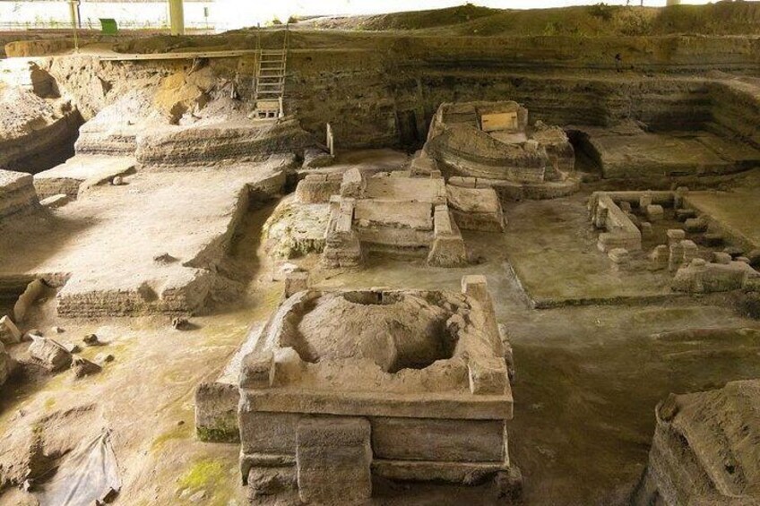An archaeological site with ancient ruins, including stone structures and a large pit. 4