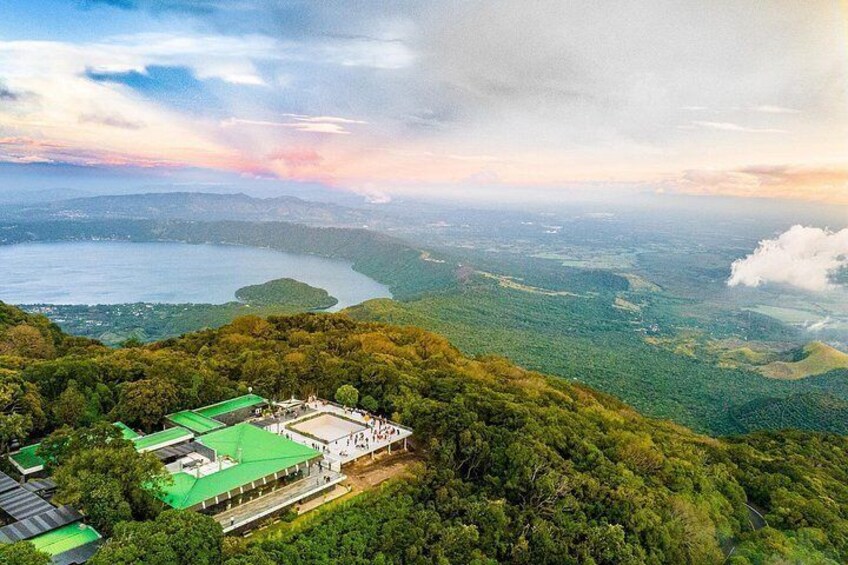 A mountainous landscape with a lake, a green-roofed building, and a road. 2