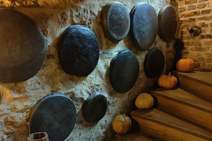 A rustic interior with a stone wall, wooden stairs, and various metal pots. 5