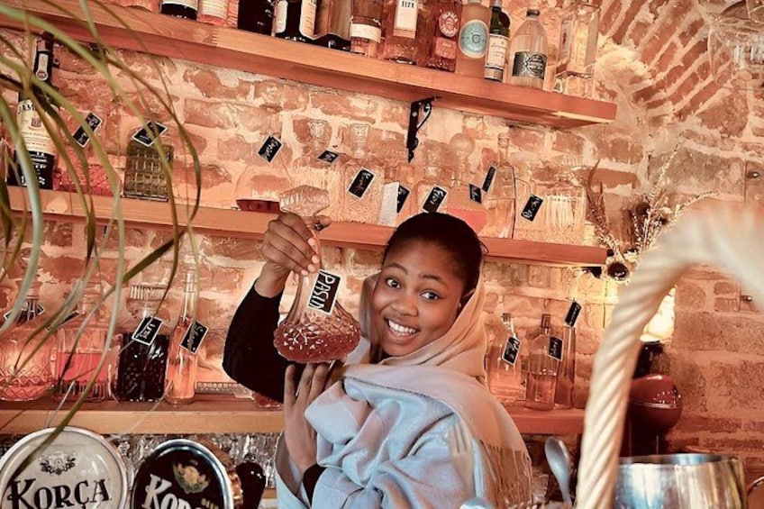 A person holding a bottle with a label, in a setting with shelves of various bottles and jars. 4