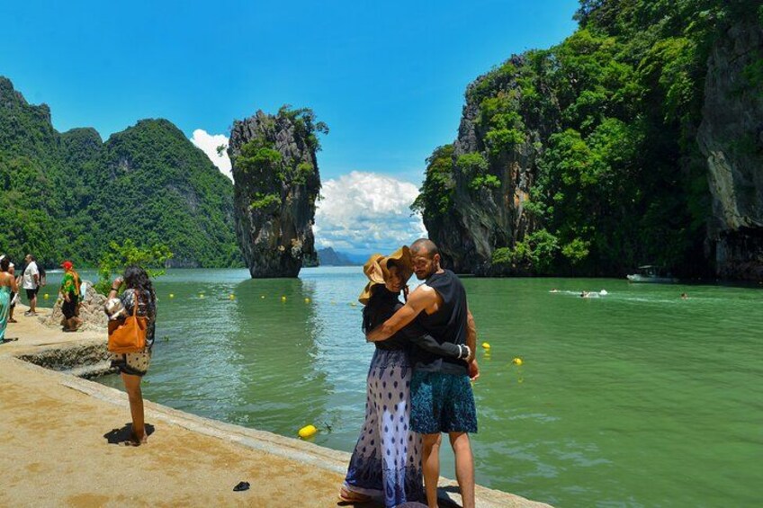 A couple embracing on a dock with a view of green cliffs and a calm river. 5