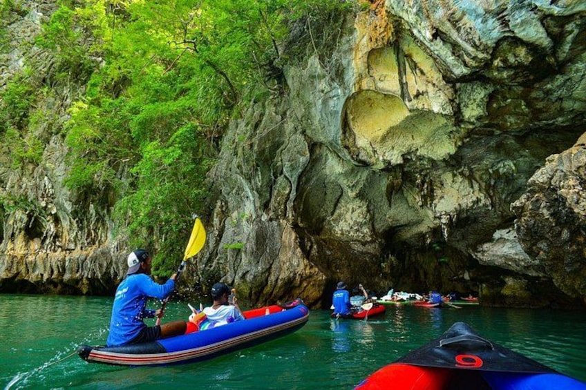 A group of kayakers navigating through a narrow waterway surrounded by rocky cliffs. 2
