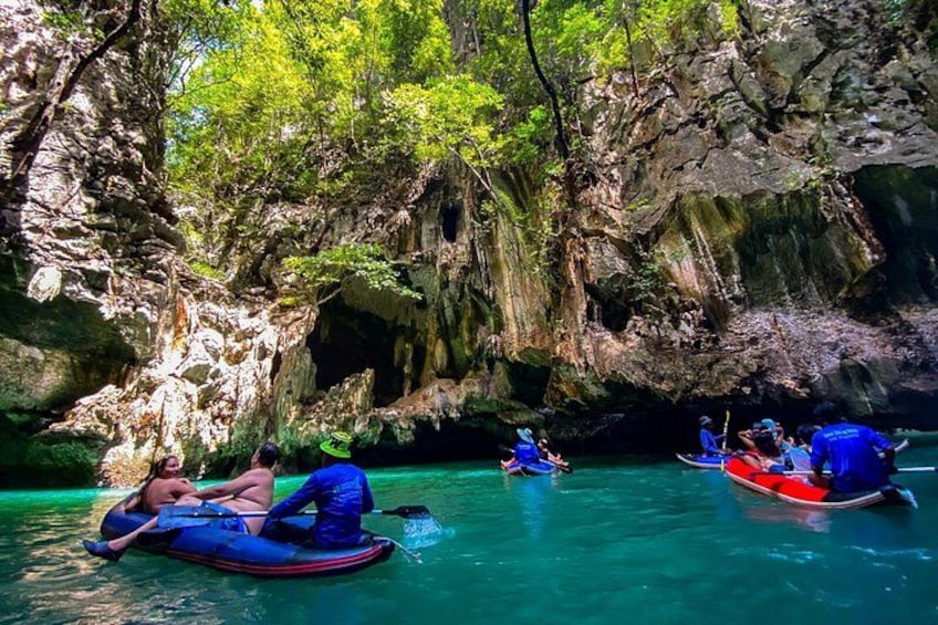 People rafting in a river surrounded by rocky cliffs and greenery. 1