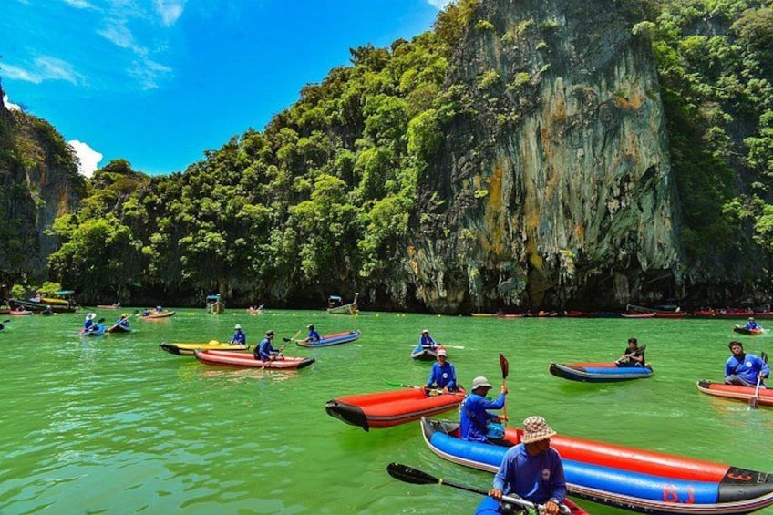 People kayaking on a green river surrounded by cliffs. 2