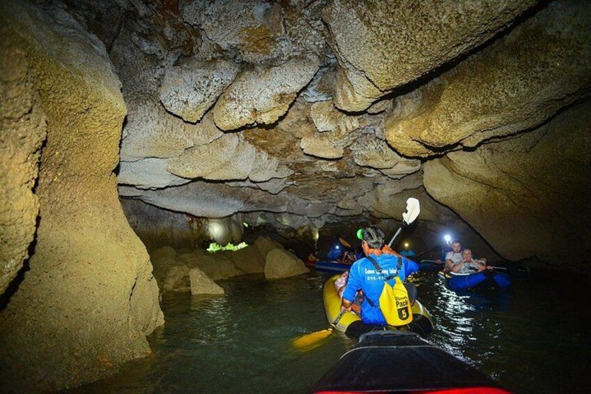People kayaking in a cave with water and rocky walls. 4