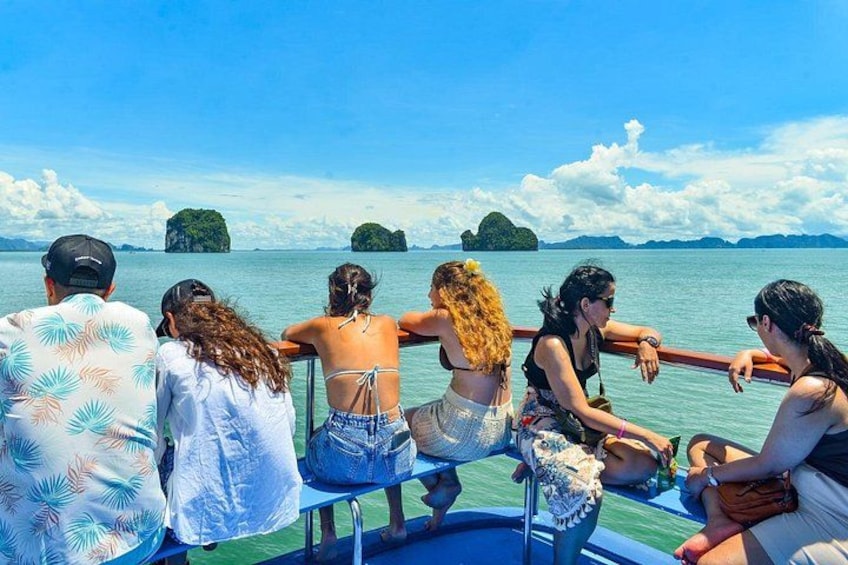 A group of people on a boat with a clear view of the sea and distant islands. 5