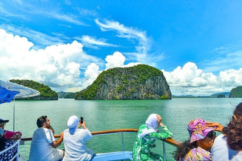 A boat with passengers taking photos of a green island in the distance. 4