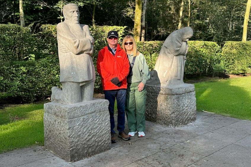 Two people standing between two stone statues in a park. 2