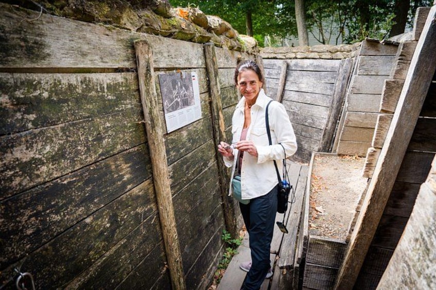 A person standing next to a wooden fence with a map attached, in a stone-walled area with steps leading up. 1