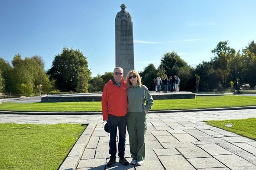 Two people standing in a park with a tall monument in the background. 5