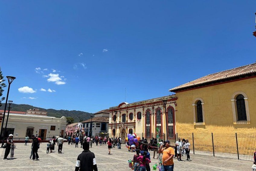 Una plaza con gente, un edificio amarillo e iglesia con columnas. 4