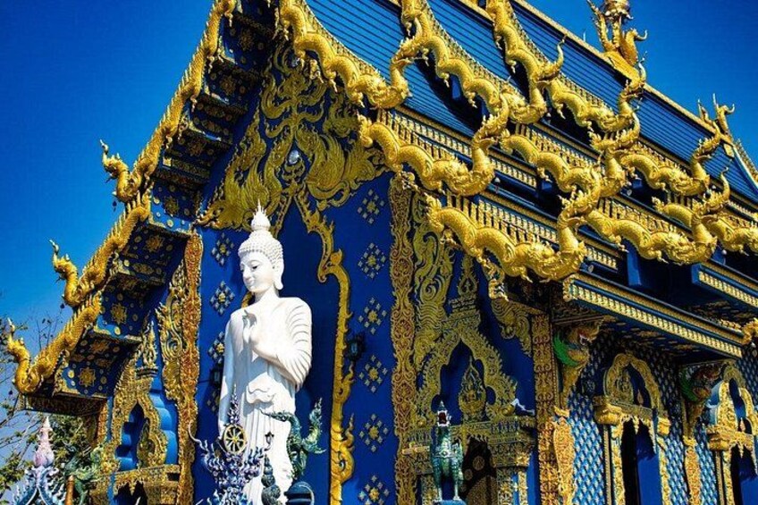 Un temple orné de motifs dorés complexes et abritant une grande statue blanche. 1