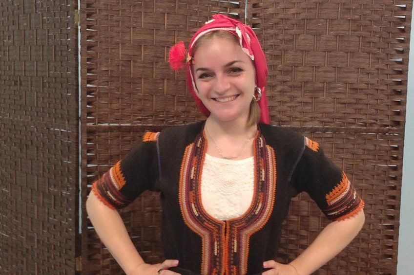 A person wearing a traditional patterned outfit with a red headscarf. 2