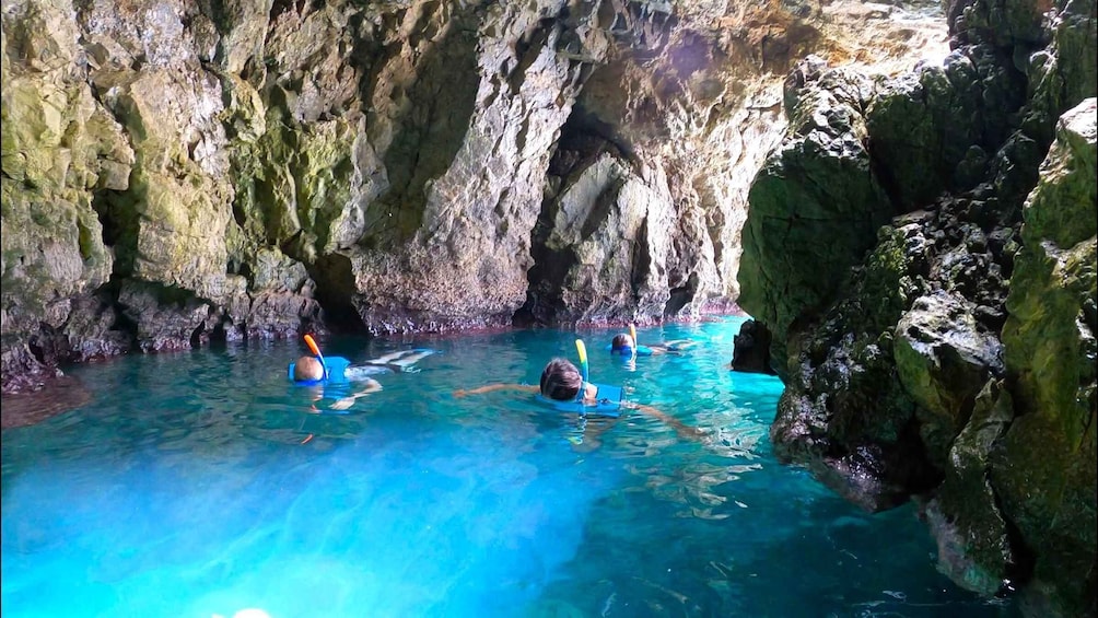 People snorkeling in a cave with clear blue water. 3