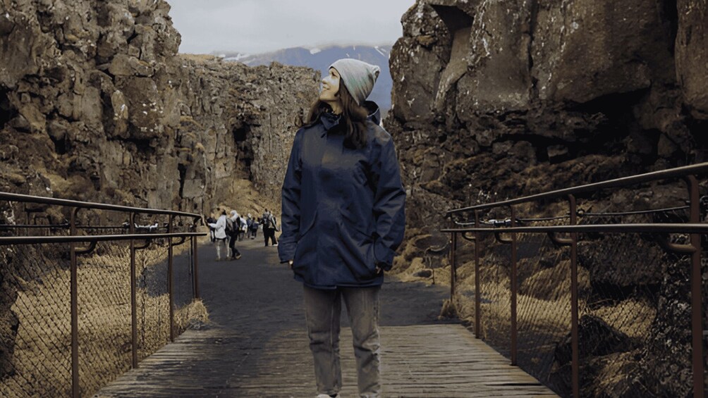 A person walking on a wooden boardwalk through a rocky canyon with metal railings on either side. 4