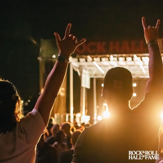 A crowd at a concert with a stage and a sign that reads 'ROCK & ROLL HALL OF FAME.' 4