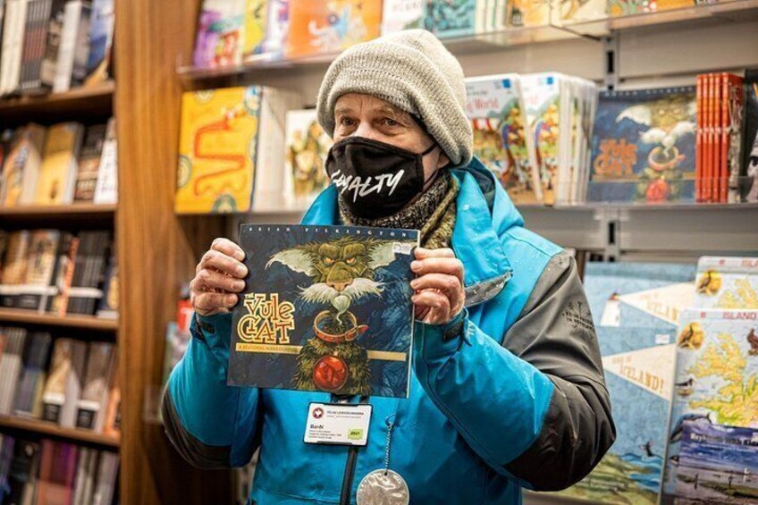 A person holding a book titled 'Yule Cat' in a bookstore. 5