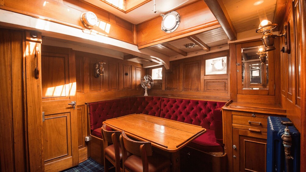 A wooden interior with a red cushioned bench, a wooden table, and a clock. 2