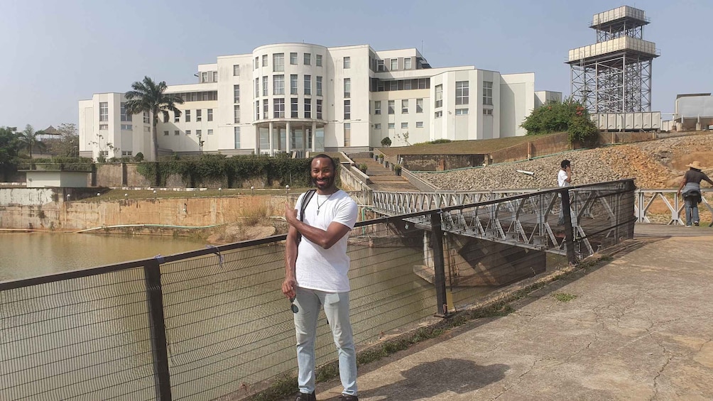 A man standing on a bridge with a river and buildings in the background. 2