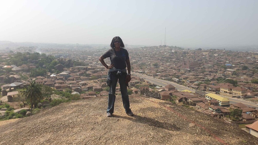 A person standing on a hill overlooking a cityscape with numerous buildings and a clear sky. 1