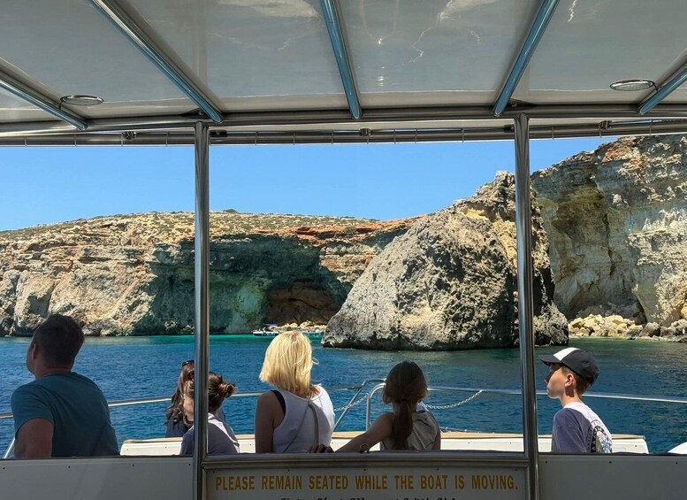 A boat with passengers looking at rocky cliffs and clear blue water. 2